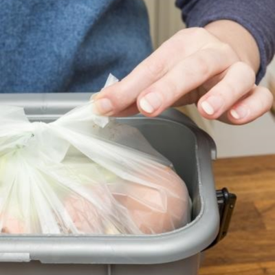 Käsi pitelee solmimaansa biojätepussia