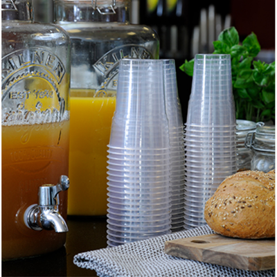 Muovisia juomakuppeja pinossa lasisen mehuhanan vieressä